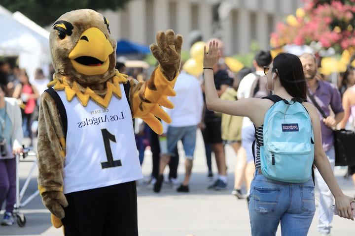 Eddie the Eagle high-fives a student.